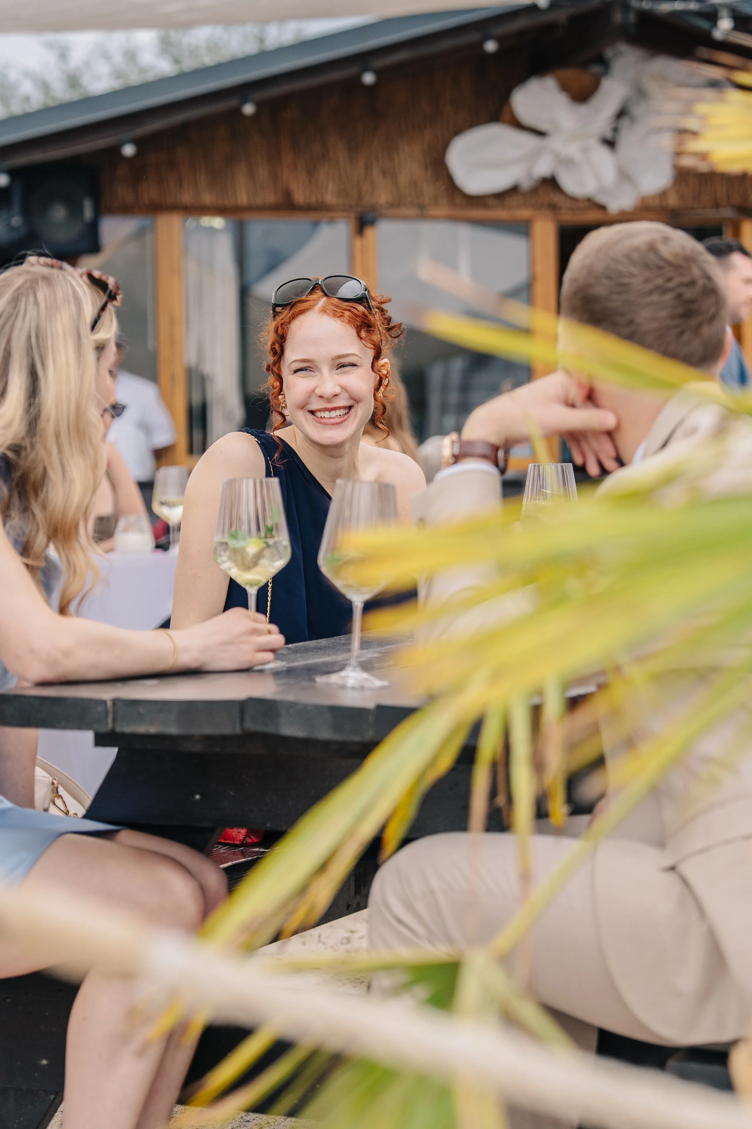Gäste mit Wein an einem Stehtisch im Beachclub
